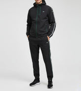 Person wearing a black tracksuit with white stripes on a light gray background